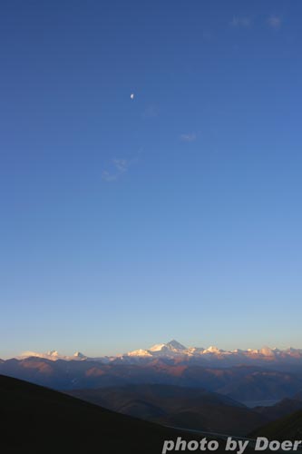 2008年4月27日，珠穆朗玛峰在日出下神秘而雄奇。珠峰上空还挂着月亮和几丝白云。